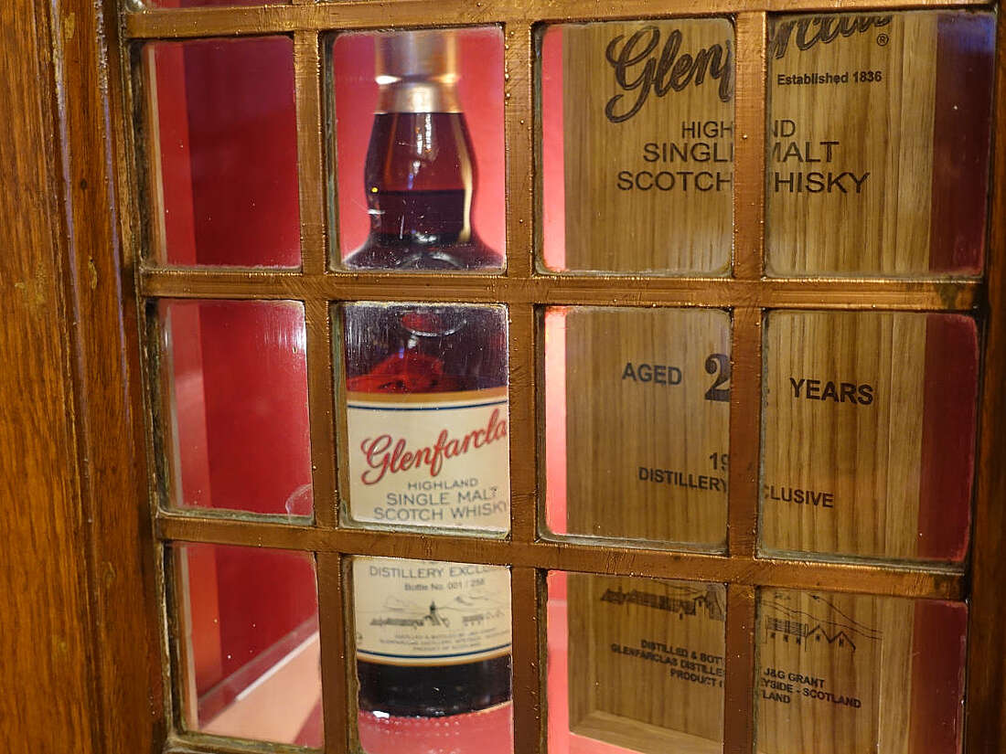 Old bottle of Glenfarclas in a cupboard behind glass