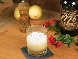 The drink Whiskey Sour in a tumbler, next to it decoration and the whisky 1776